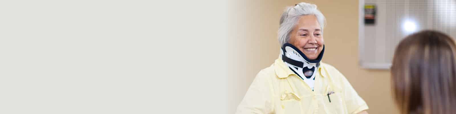 a caregiver with an elderly resident wearing a neck brace at the Cottonwood Canyon Healthcare facility